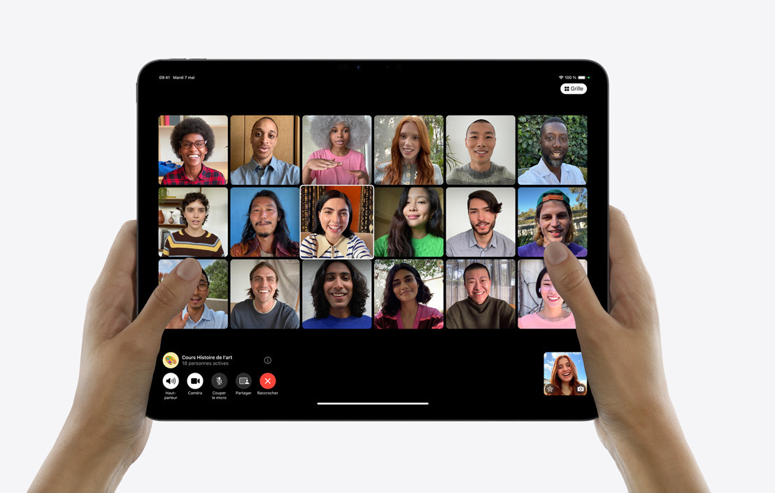Deux mains tenant un iPad Pro montrant un appel FaceTime de groupe.