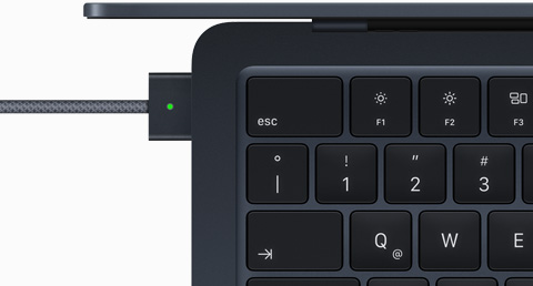Imagen desde arriba de un cable MagSafe conectado a una MacBook Air color medianoche
