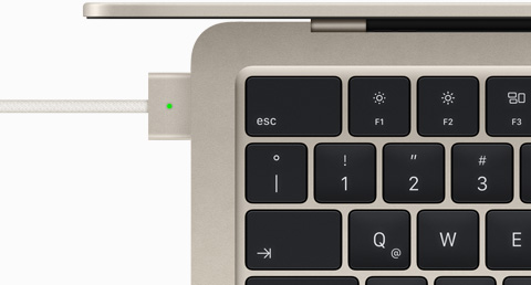 Imagen desde arriba de un cable MagSafe conectado a una MacBook Air blanco estelar