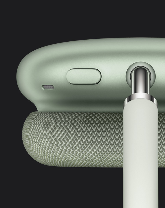 Žalios spalvos „AirPods Max“ triukšmo valdymo mygtuko, kuris yra ausų kaušelio viršuje ties ta vieta, kurioje jungiasi laikiklio vamzdelis, vaizdas stambiu planu