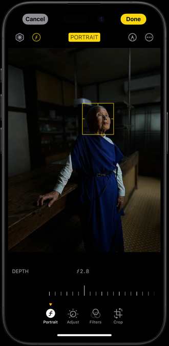Ein iPhone 15 Pro zeigt das Porträt einer Frau, das in einer Umgebung mit wenig Licht aufgenommen wird, wobei der anpassbare Fokus auf ihrem Gesicht liegt