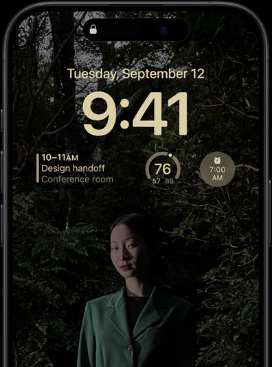 Niegasnący wyświetlacz iPhone’a 15 Pro przedstawiający ekran blokady z widżetem apki Kalendarz, widżetem apki Pogoda i widżetem budzika