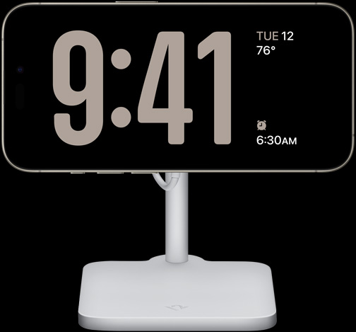 iPhone 15 Pro Készenlét módban, amelynek a kijelzőjén egy teljes képernyős óra jelenik meg az aktuális hőmérséklettel és a következő ébresztés időpontjával