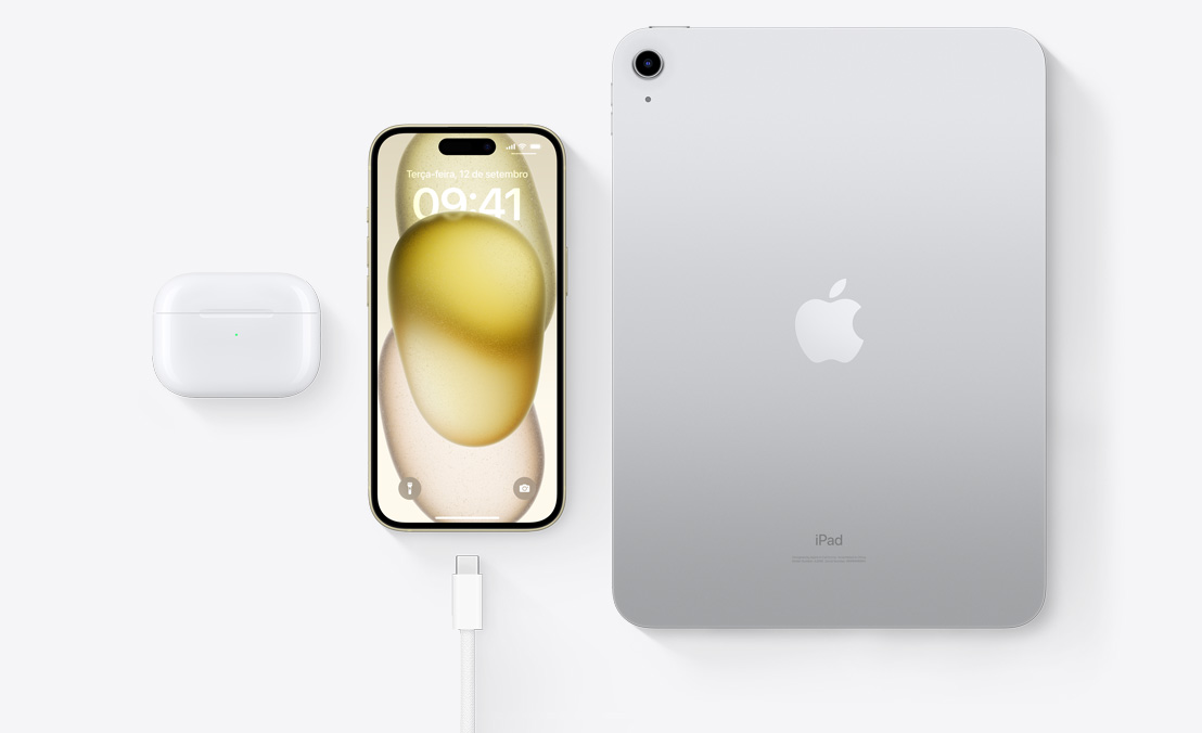 Imagem aérea dos AirPods Pro, do iPhone 15 e de um iPad com conector USB-C para demonstrar como os três aparelhos podem ser recarregados com o mesmo cabo USB-C.