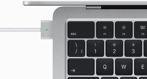 Vue en plongée d’un MacBook Air argent auquel est branché un câble MagSafe de la même couleur