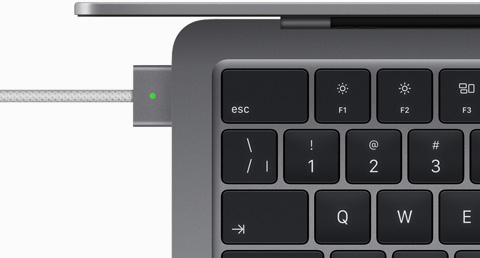 Vue en plongée d’un MacBook Air gris cosmique auquel est branché un câble MagSafe de la même couleur