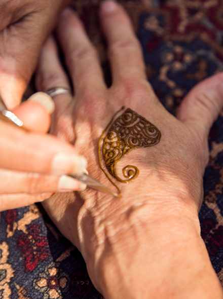 特写照片，一个人的手在另一个人的手上描绘海娜纹身。
