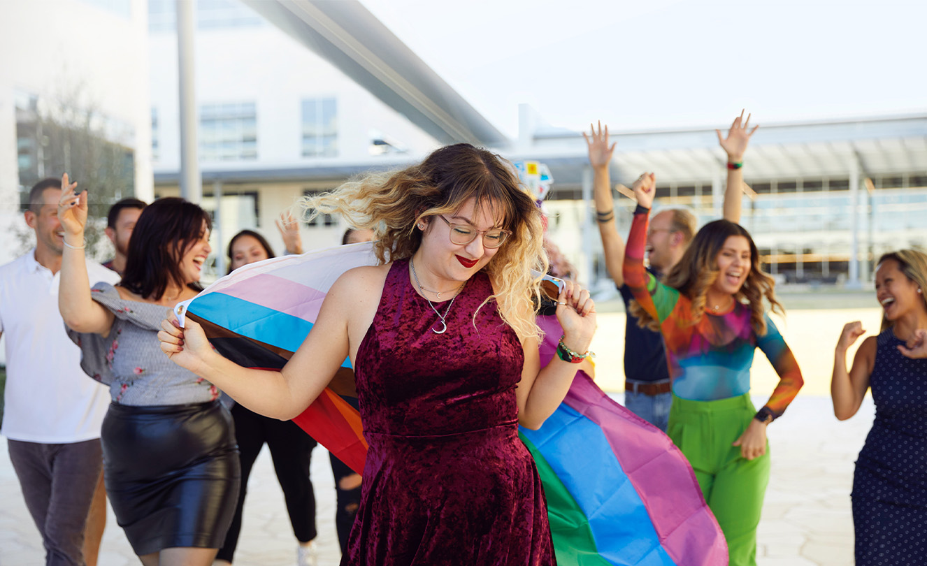 Eine Gruppe von Apple Teammitgliedern tanzt und feiert im Freien. 