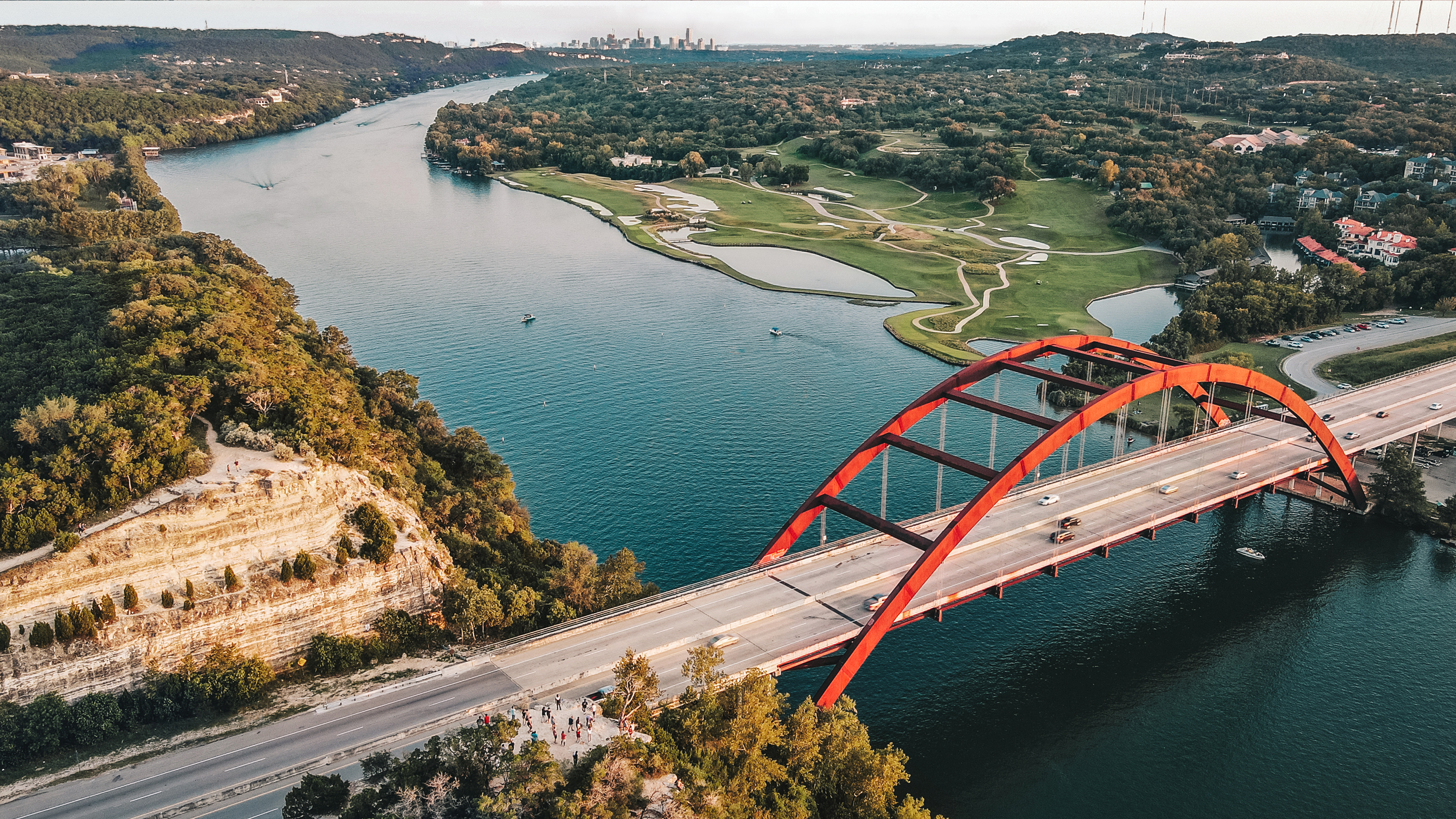 Aerial view of a river and a bridge in Austin, Texas, with the city in the background. 