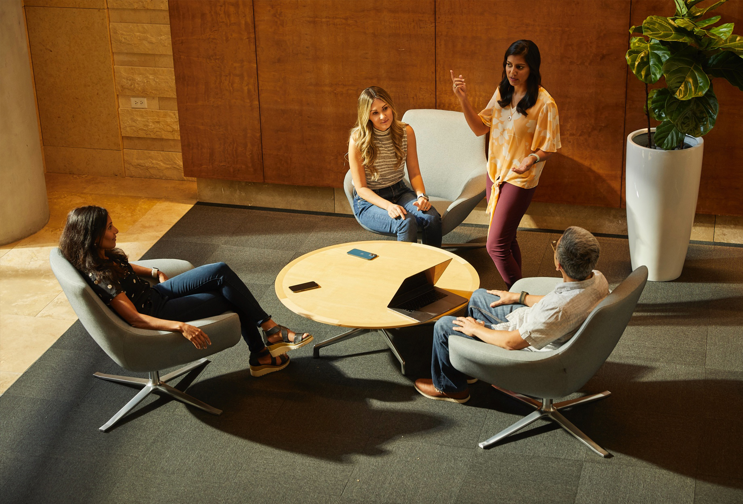 Cuatro empleados de Apple hablan y colaboran sentados en un espacio tranquilo.