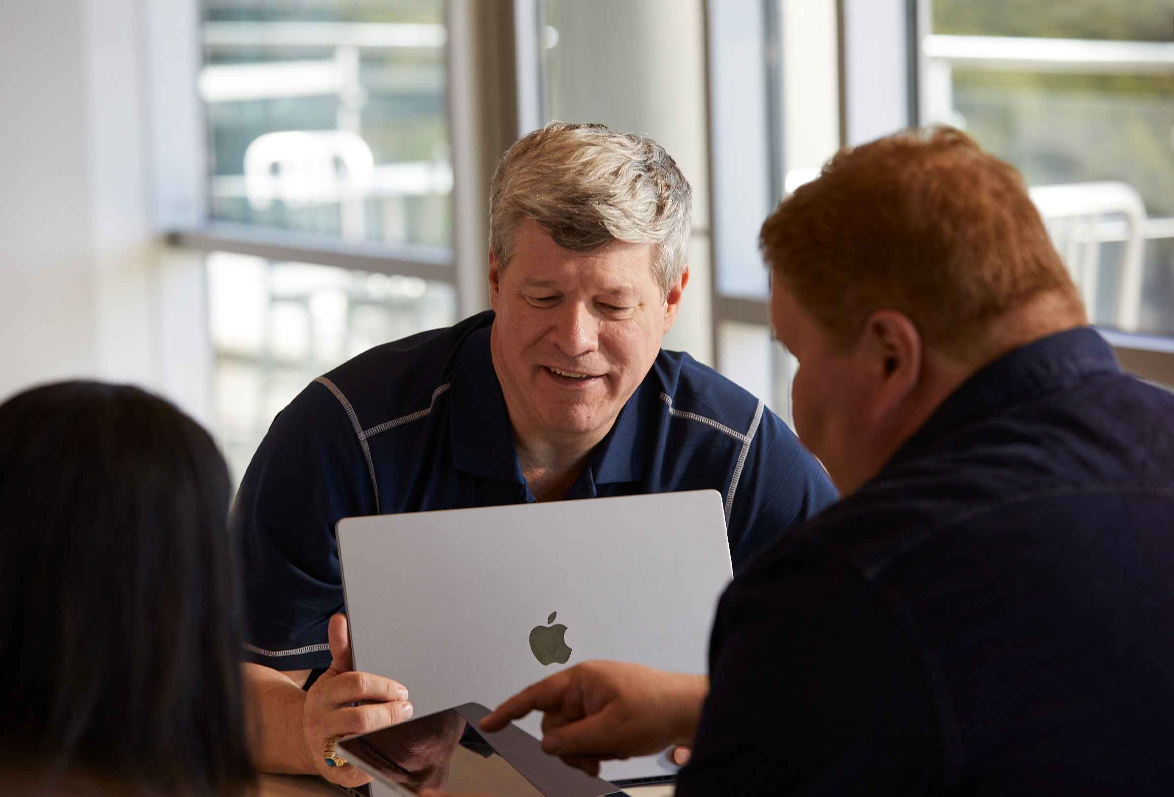 Üç Apple çalışanı ortak çalışma sırasında bir MacBook ve iPad kullanıyor.