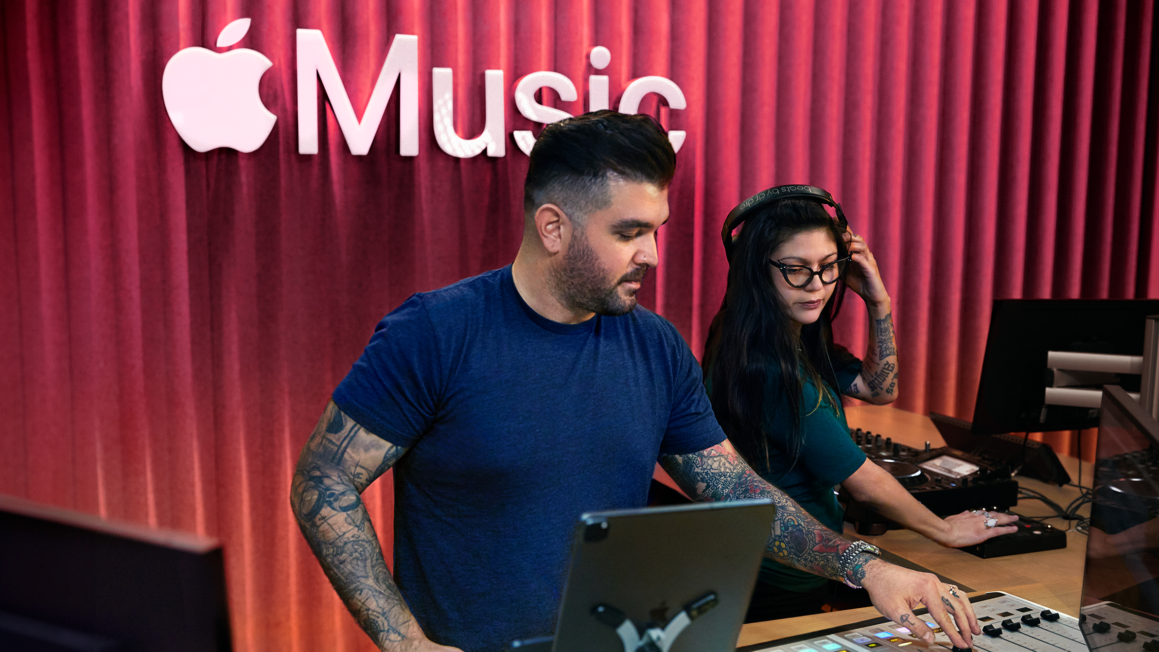 Apple Musicのスタジオでサウンドミキシングボードを操作している2人のApple社員。