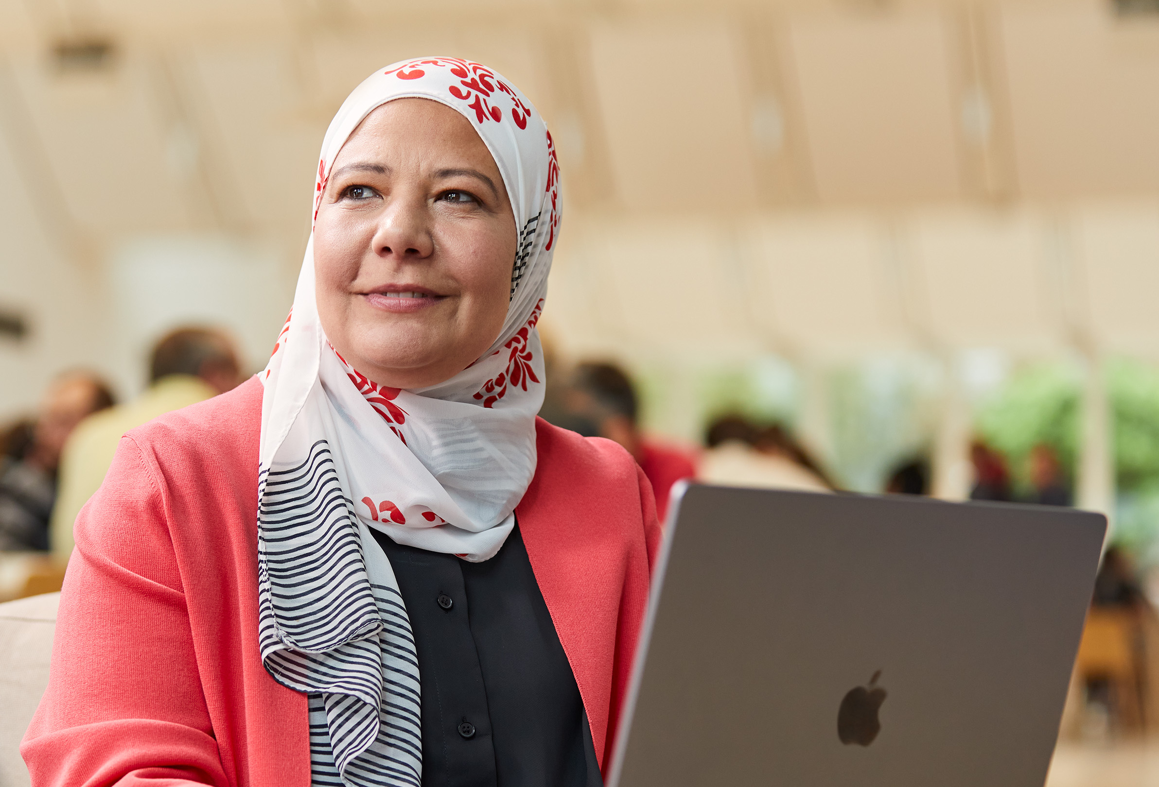 Uma funcionária da Apple sentada a olhar para a esquerda, a trabalhar num MacBook.