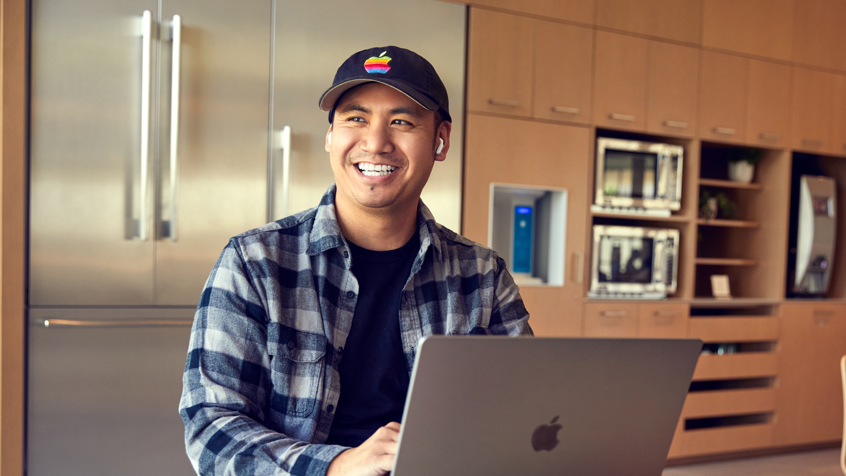 Een medewerker van Apple San Diego die lachend op zijn laptop zit te werken.