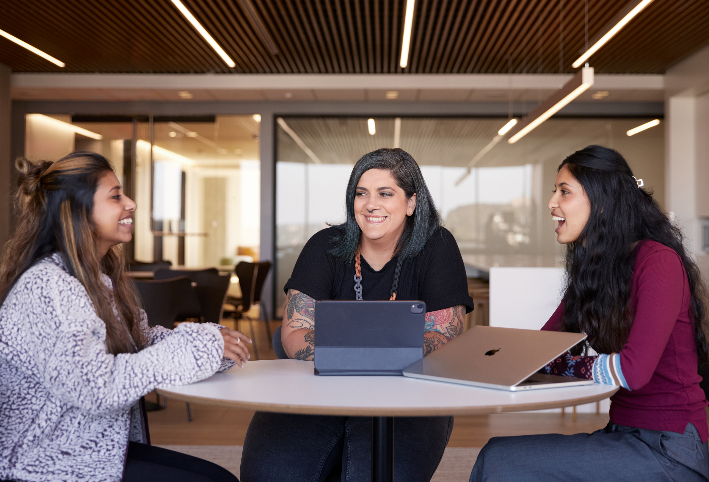 Tres empleadas de Apple hablan sentadas en una mesa.