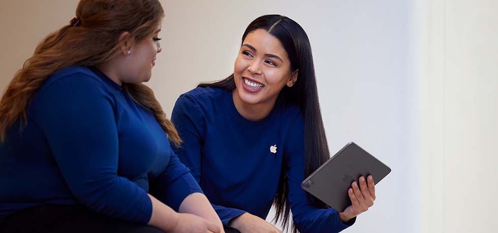 Carissa sujetando un iPad y hablando con otra persona del equipo de Apple Retail.