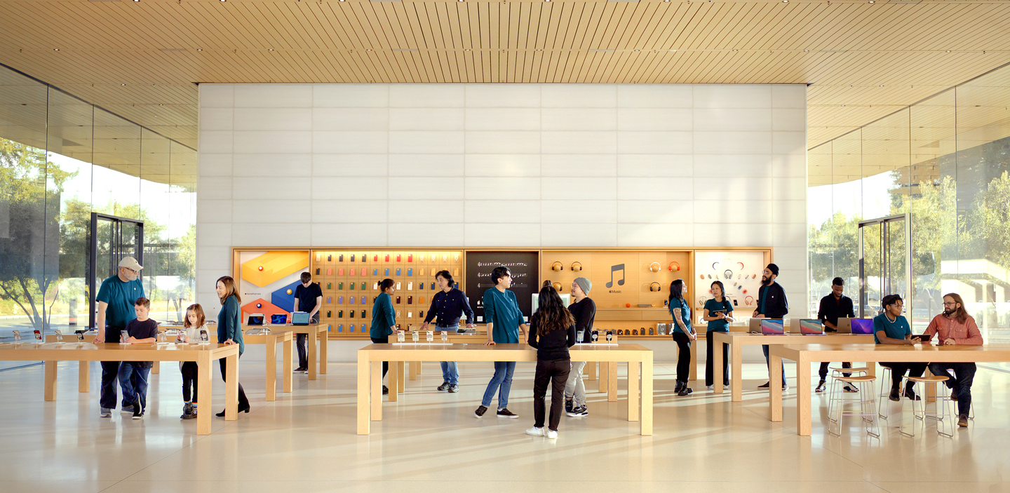Çeşitli noktalarda ayakta duran çalışanların yer aldığı bir Apple Store görseli.
