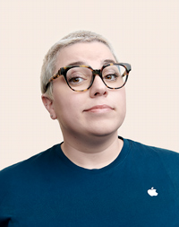 Membre de l’équipe de vente au détail Apple aux cheveux courts, portant des lunettes et regardant l’objectif.