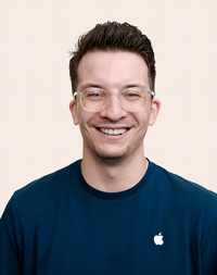 Funcionário da Apple Retail de cabelo curto e castanho sorrindo para a câmera. 