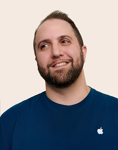 Apple Retail employee smiling and looking away from the camera.