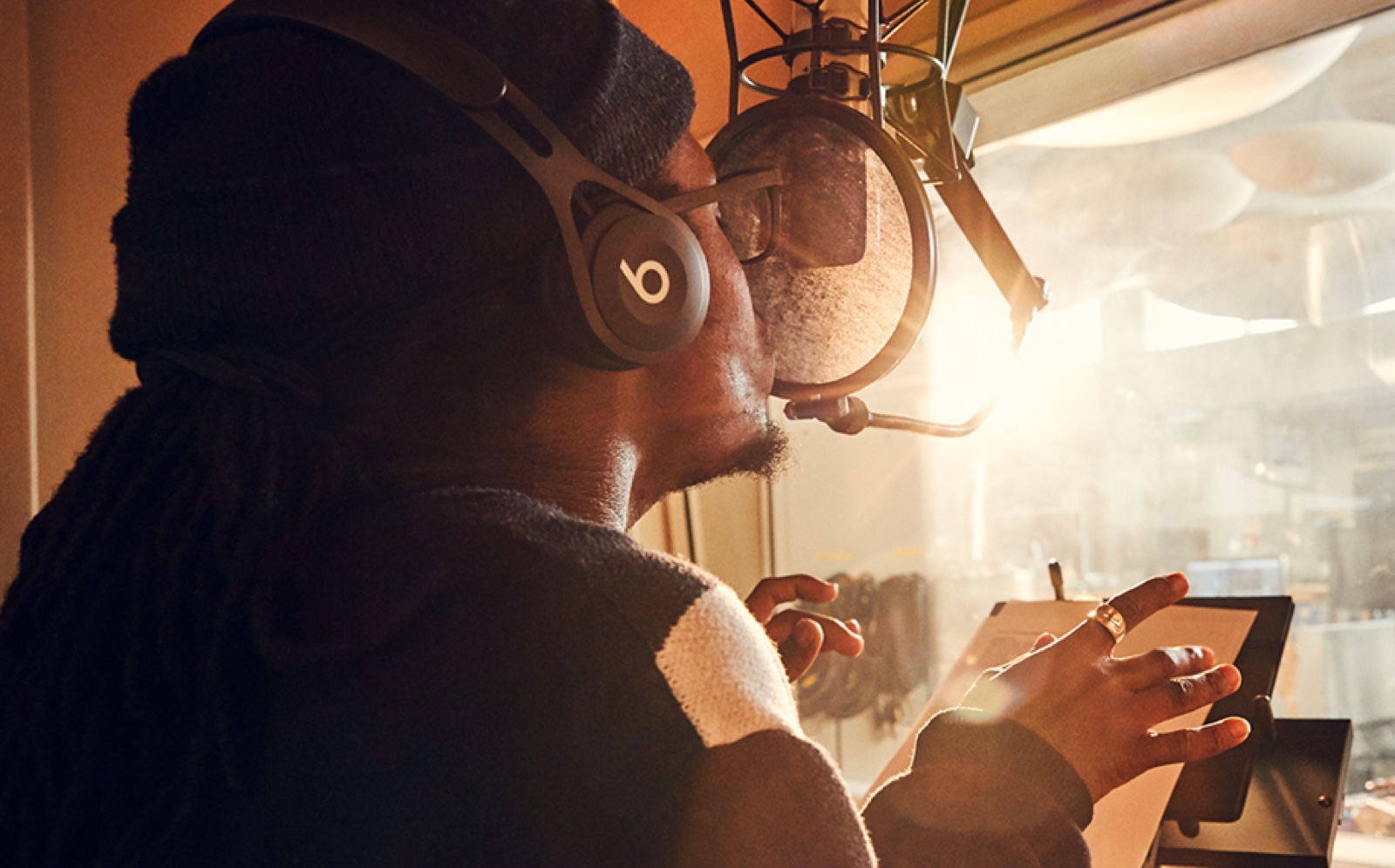 A male Apple Store employee sings into a microphone in a professional music studio.