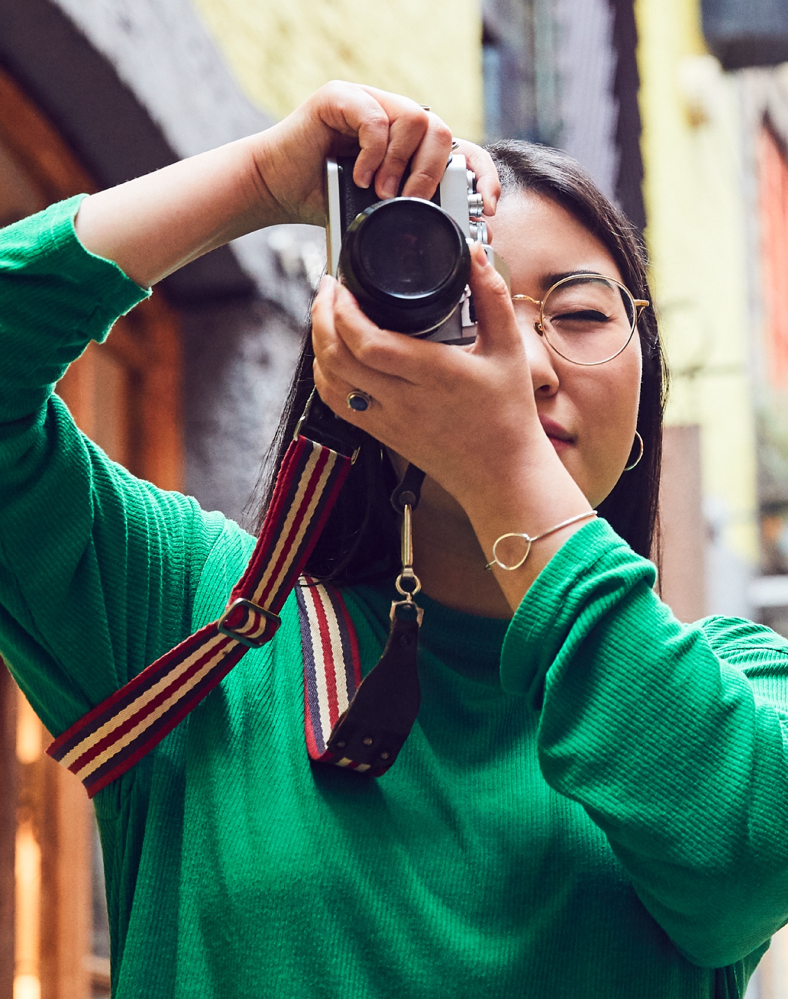 街の通りで、昔ながらの35ミリカメラを使って写真を撮るApple Storeの女性スタッフ。