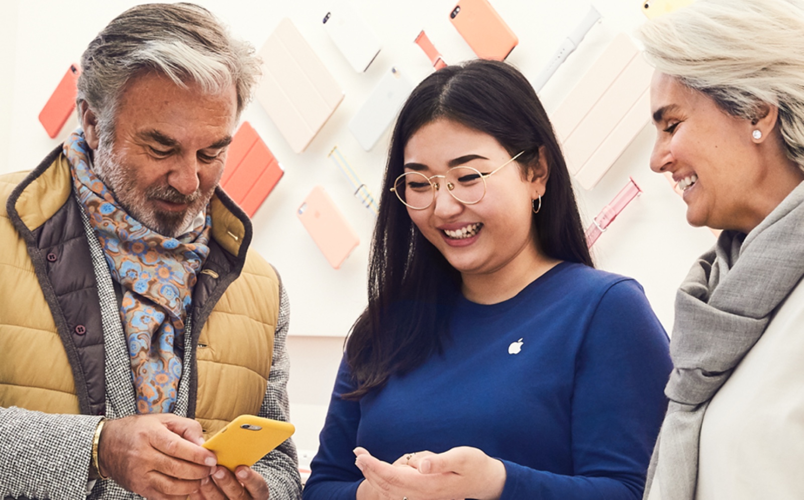 Apple Store에서 여성 직원이 두 명의 고객에게 iPhone 사용법을 알려주는 모습