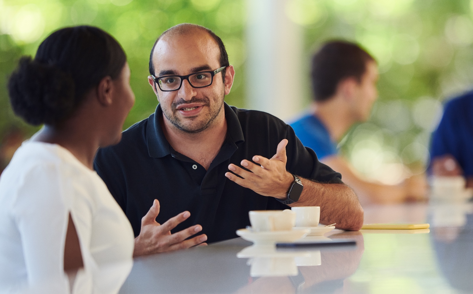 Dois funcionários conversam em uma cafeteria em um campus da Apple.