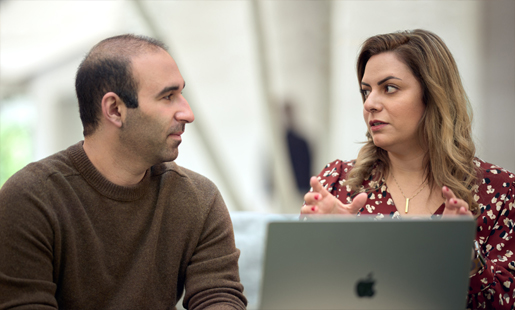 Desireh, sentada em frente a um MacBook, a conversar com um colega