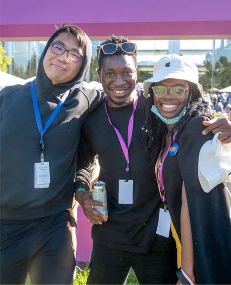 Trois stagiaires d’Apple debout, les bras autour des épaules, souriant à la caméra.