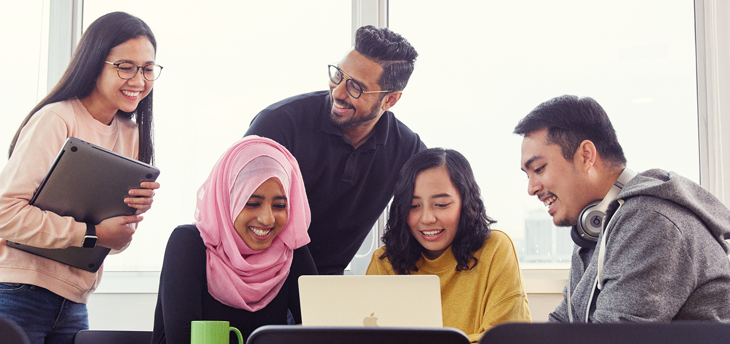 Des employés Apple se regroupent pour discuter en regardant le MacBook d’une de leurs collègues.