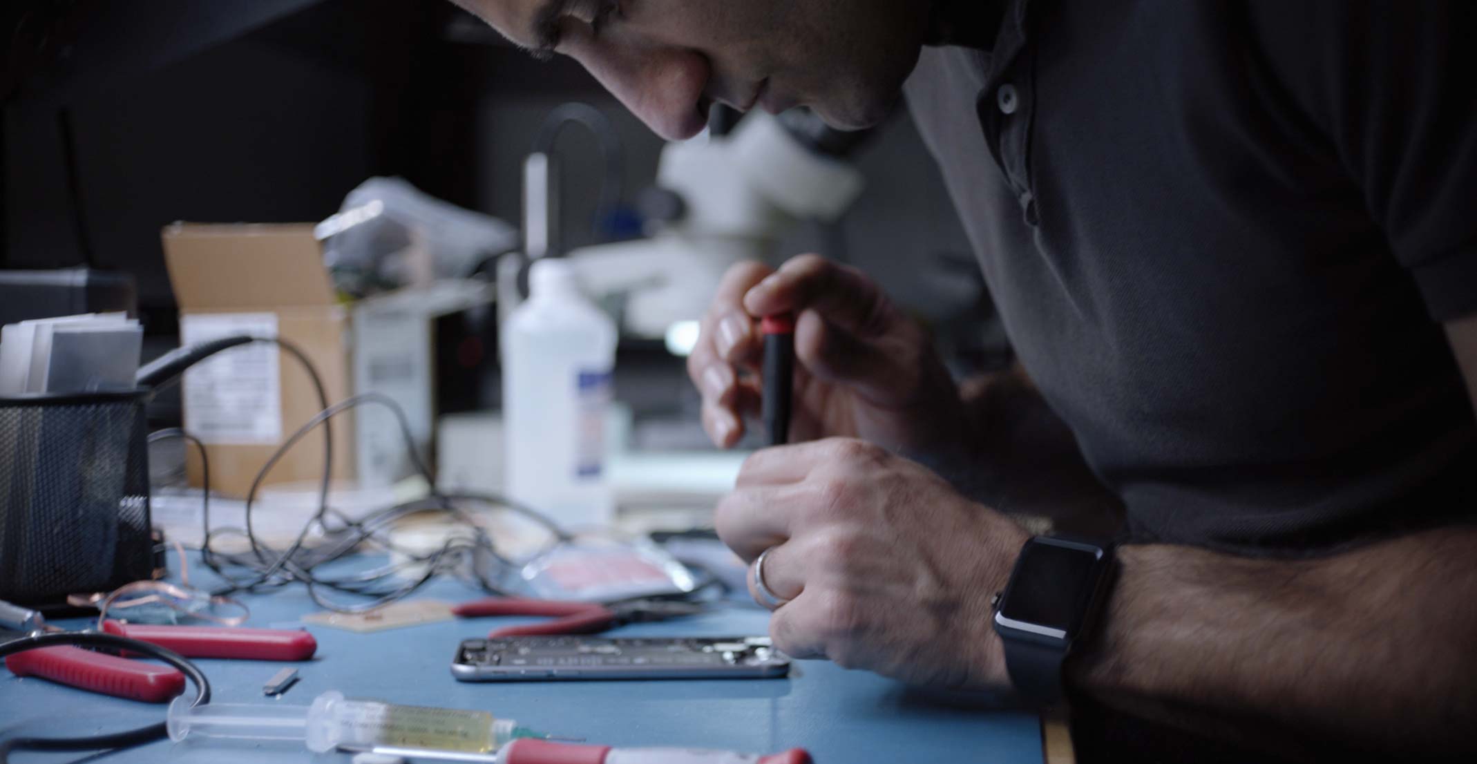 Apple Sensing Product Design 團隊的工程經理 Ehsan 在工程實驗室裡操作一部 iPhone。