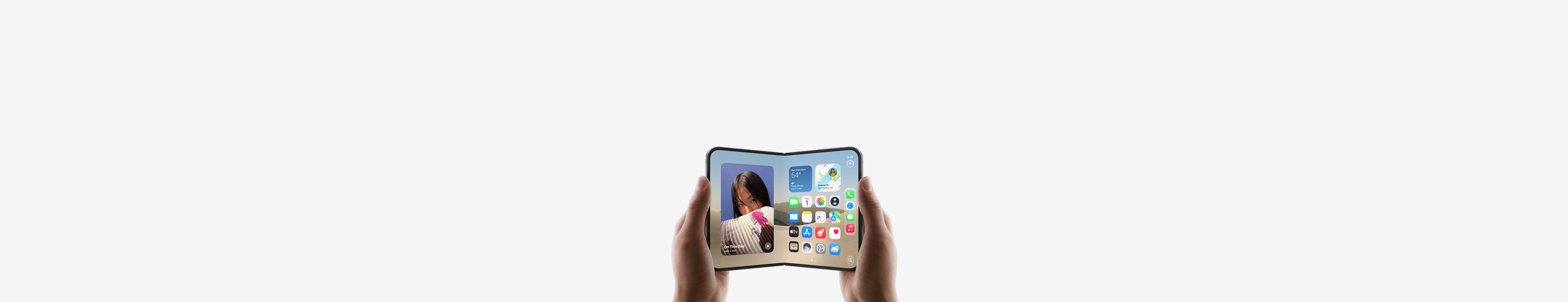 iPhone Duo, dos manos lo sostienen en posici&oacute;n horizontal, desplegado, la pantalla interior muestra la pantalla de inicio