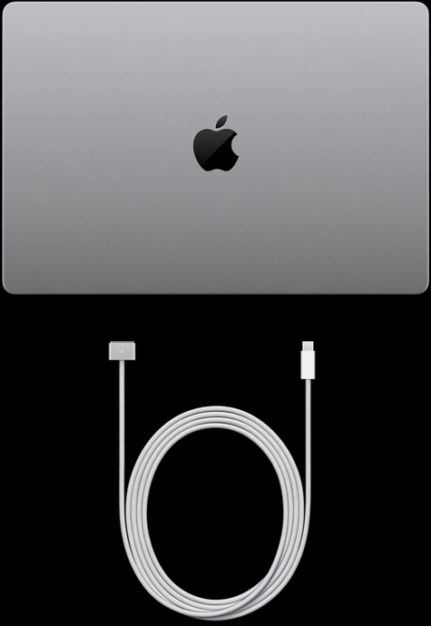 Zavřený MacBook&nbsp;Pro s&nbsp;PROLED&nbsp;XDR displejem, stříbrná barva, pohled shora, USB‑C nabíjecí kabel a napájecí adaptér