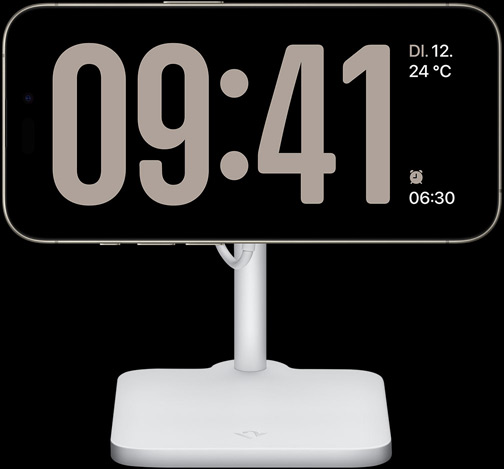 Ein iPhone 15 Pro in StandBy zeigt eine Uhr im Vollbildmodus mit dem Datum, der Temperatur und dem nächsten Wecker