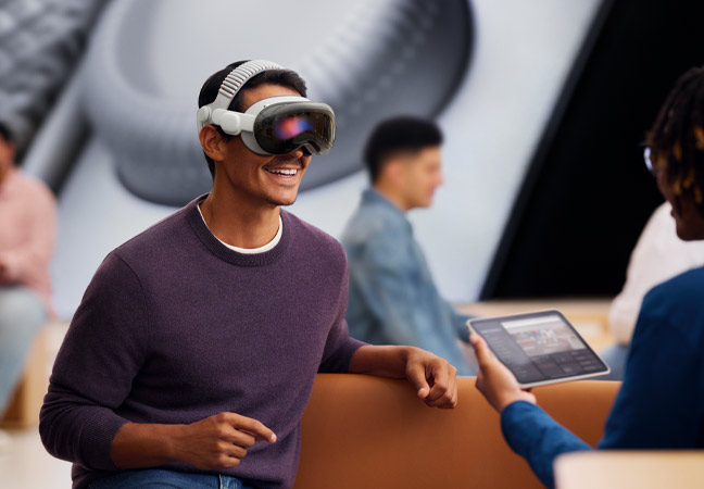 Customer at an Apple Store wearing Apple Vision Pro experiencing a one-on-one demo with a Specialist