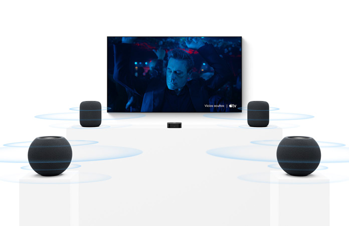 Apple TV 4K, pantalla de televisión, dos altavoces HomePod color medianoche a la izquierda y a la derecha, dos altavoces HomePod mini 2 color medianoche en primer plano, ondas sonoras concéntricas se propagan desde cada altavoz