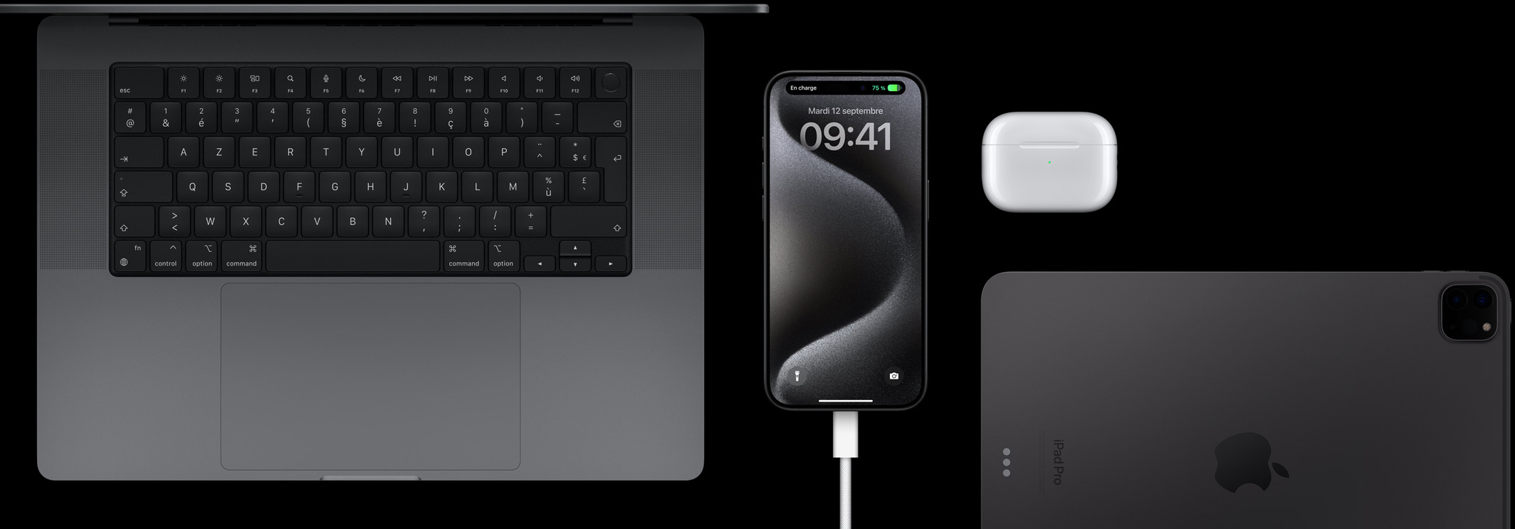 Un iPhone 15 Pro connecté à un câble USB-C, entouré d’un MacBook Pro, d’AirPods Pro et d’un iPad