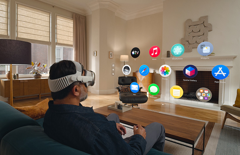 一位使用者戴著 Apple Vision Pro 坐在客廳的梳化上，啟動主畫面