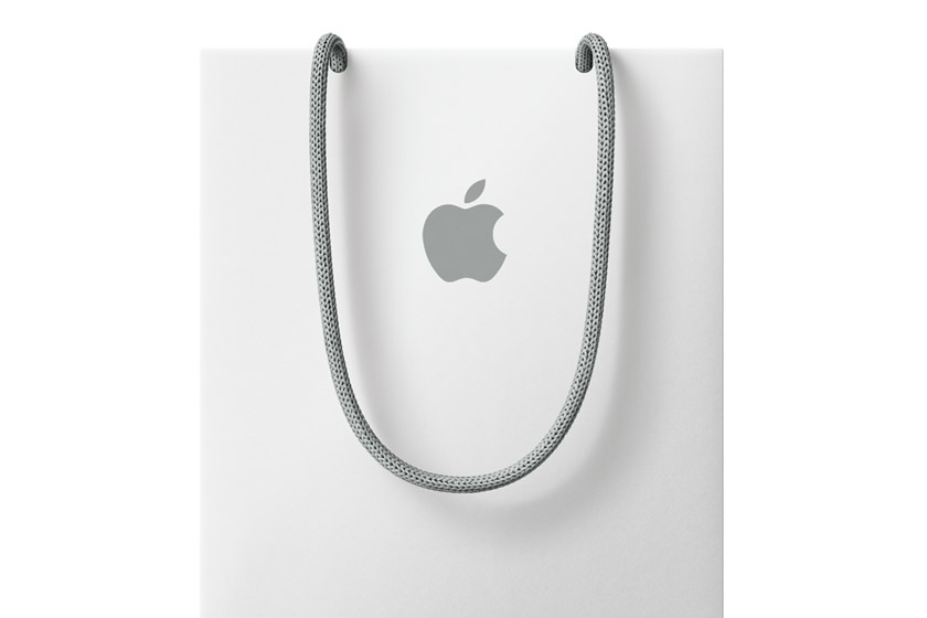 白色禮品袋，中央印有 Apple 標誌，配以灰色穿繩手挽