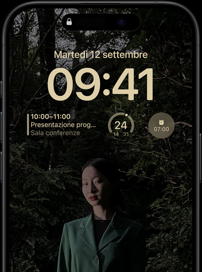 Una schermata di blocco sul display always-on di iPhone 15 Pro, con un widget del calendario, un widget del meteo e un widget della sveglia