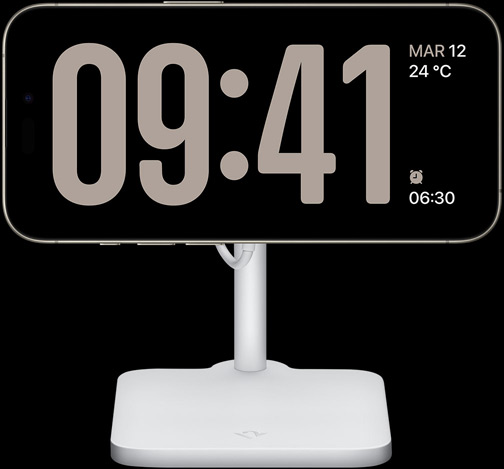 Il display di un iPhone 15 Pro in modalità Standby con un orologio a tutto schermo insieme alla data, la temperatura e la prossima sveglia