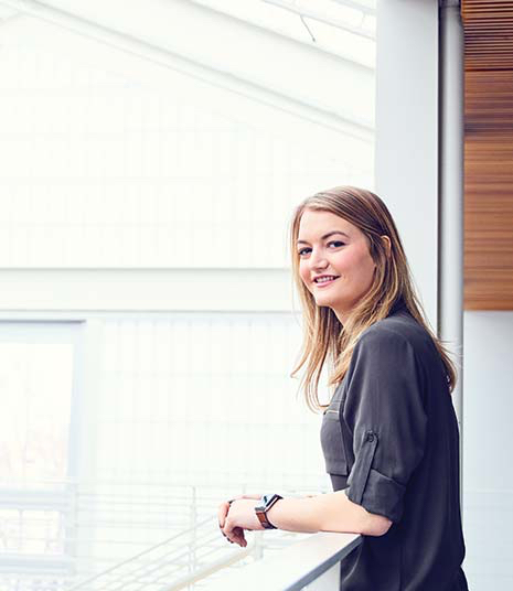 Hymyilevä opiskelija seisoo ikkunan edessä