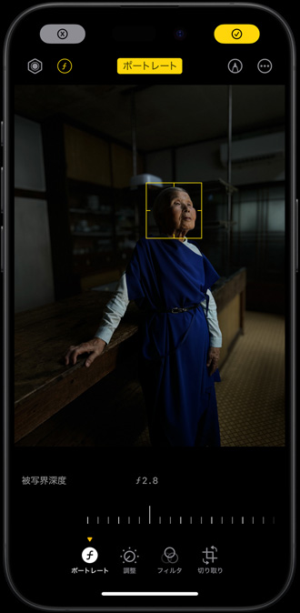 薄暗い場所で撮影中の女性のポートレートがiPhone 15 Proに表示されている。調節できる焦点が女性の顔に合わせられている
