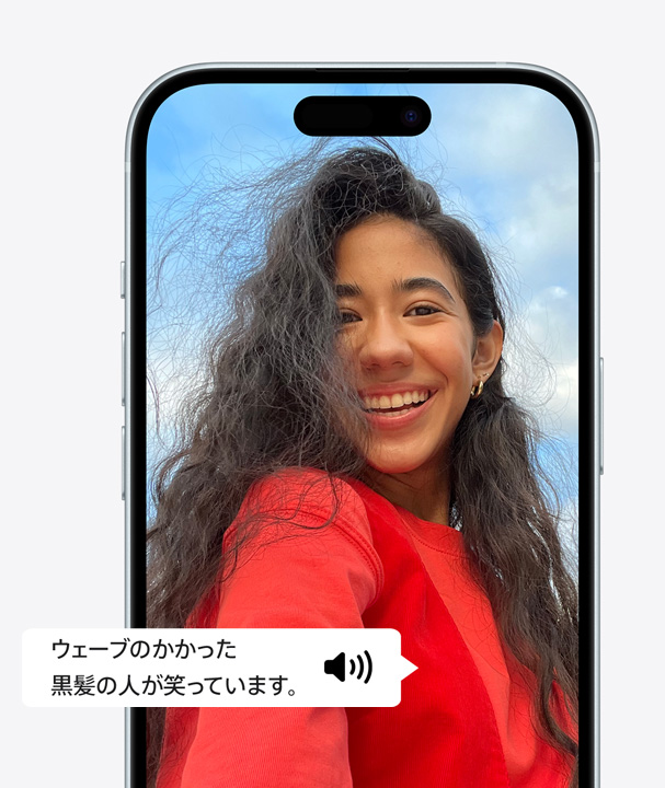 VoiceOverを使って、ウェーブのかかった髪の人物が笑っていることを説明しているiPhoneの画像。