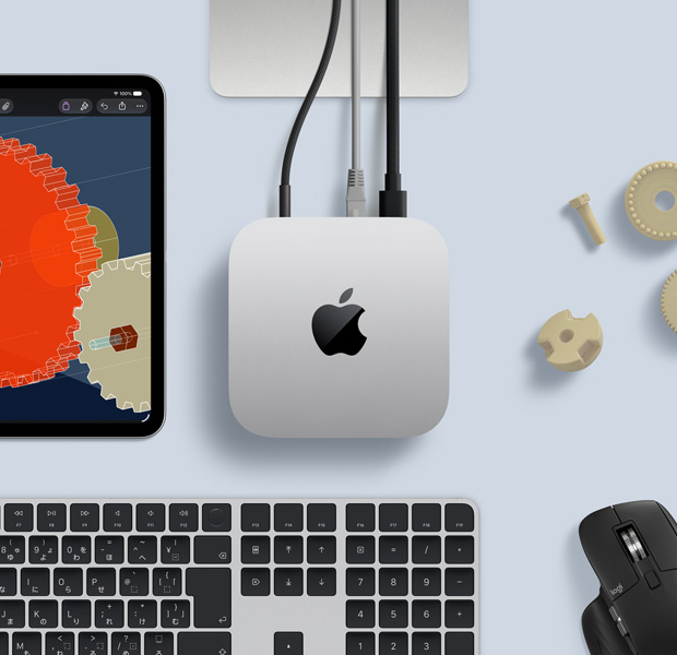 iPadに細部まで描かれたSTEM関連のオブジェクトが表示されている。中央にMac miniがあり、電源ケーブルが接続されている。Studio Displayのスタンドが一部見えていて、USB-Cで接続されている。Touch ID搭載Magic KeyboardとLogicoolのマウス
