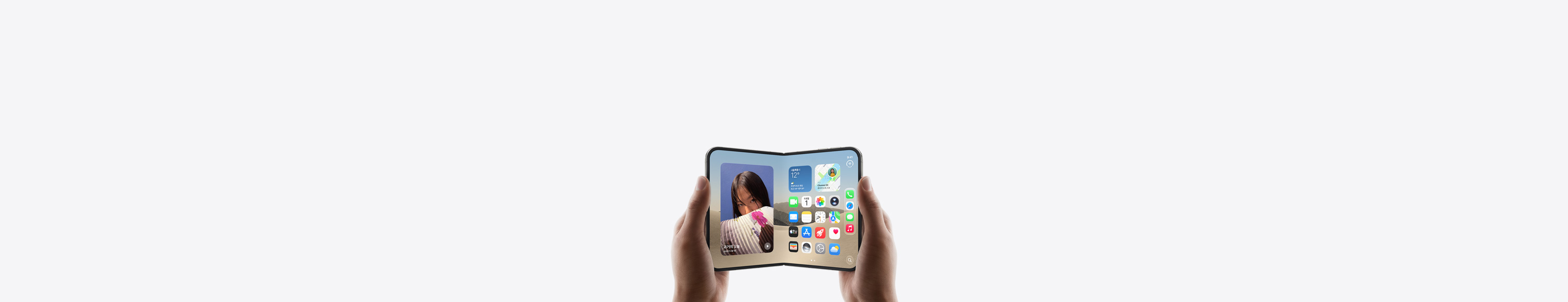 iPhone Duo를 가로 방향으로 펼친 상태에서 두 손으로 들고 있는 모습. 내부 디스플레이에 홈 화면이 보입니다.