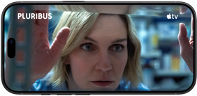 „iPhone 18 Pro“, horizontalioje padėtyje, stambiu planu rodoma moteris, žiūrinti pro lentyną. Serialo pavadinimas: „Pluribus“