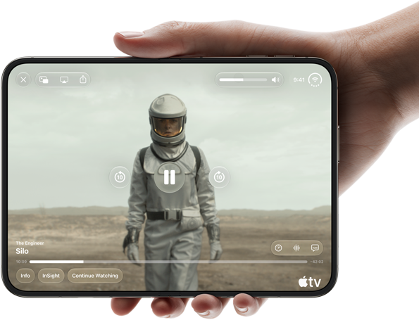 „iPhone Duo“, laikomas viena ranka, atidarytas horizontalia padėtimi, visiškai atlenktas, vidinis ekranas rodo „Apple TV“ serialą „Silo“