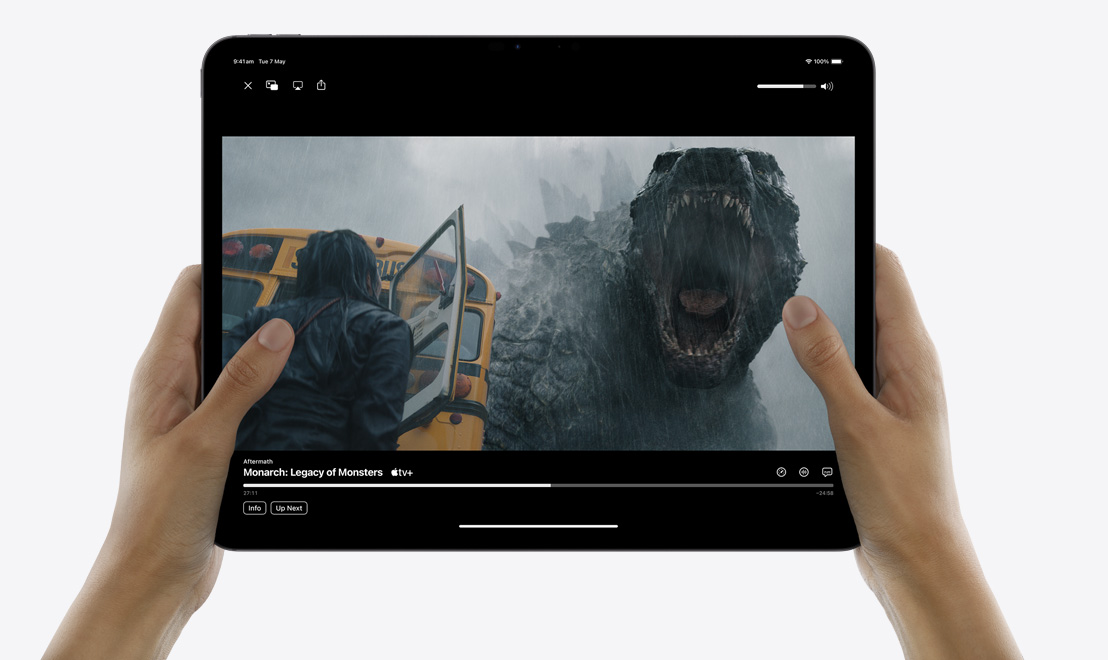 Rokās tiek turēts iPad Pro, kura atvērta TV aplikācija; tiek atskaņots seriāls Monarch: Legacy of Monsters.